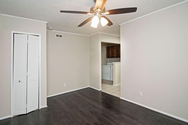 Empty room with ceiling fan, a textured ceiling, ornamental molding, hardwood / wood-style flooring, and separate washer and dryer | Image 12