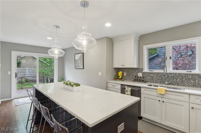 Kitchen featuring tasteful backsplash, stainless steel dishwasher, a sink, light countertops, and a kitchen island | Image 19