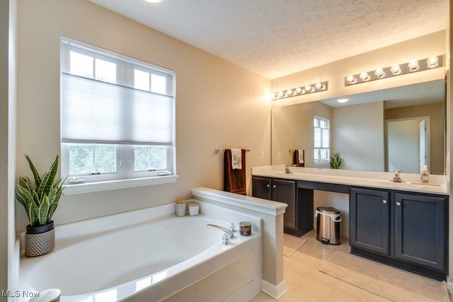 Full bath featuring double vanity, a garden tub, tile patterned floors, and a textured ceiling | Image 24