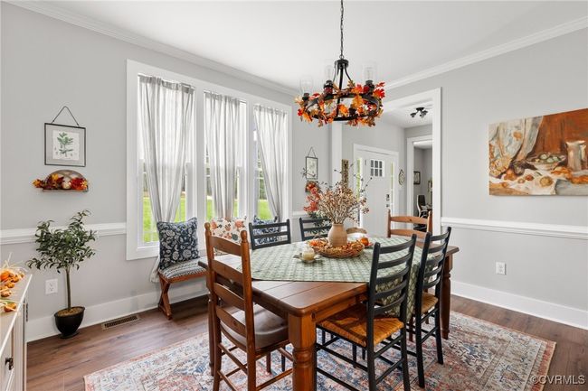 Dining room with an inviting chandelier, a healthy amount of sunlight, ornamental molding, and visible vents | Image 11