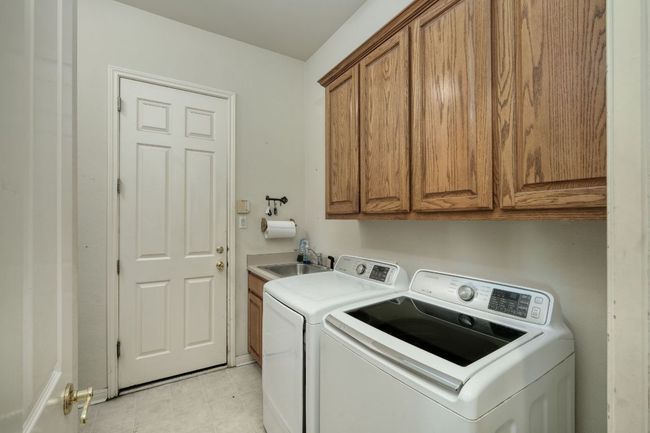 Laundry area featuring washing machine and dryer, cabinet space, and a sink | Image 26