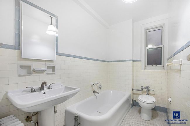 Full bath with a wainscoted wall, tile patterned floors, toilet, tile walls, and a garden tub | Image 11