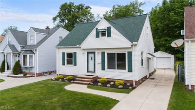 Cape cod-style house with a garage, a front lawn, and an outdoor structure | Image 2