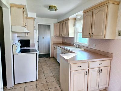 Kitchen featuring light brown cabinets, sink, light tile patterned floors, and white appliances | Image 3