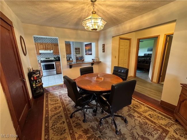 Dining space featuring dark wood finished floors, a textured ceiling, and a chandelier | Image 13