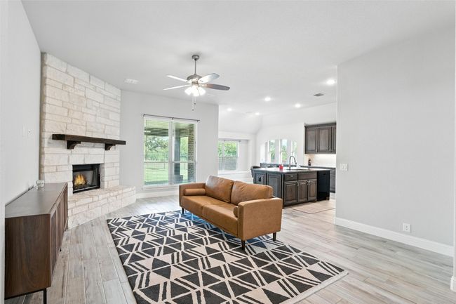 Living room featuring a stone fireplace, a ceiling fan, and light wood-type flooring | Image 9