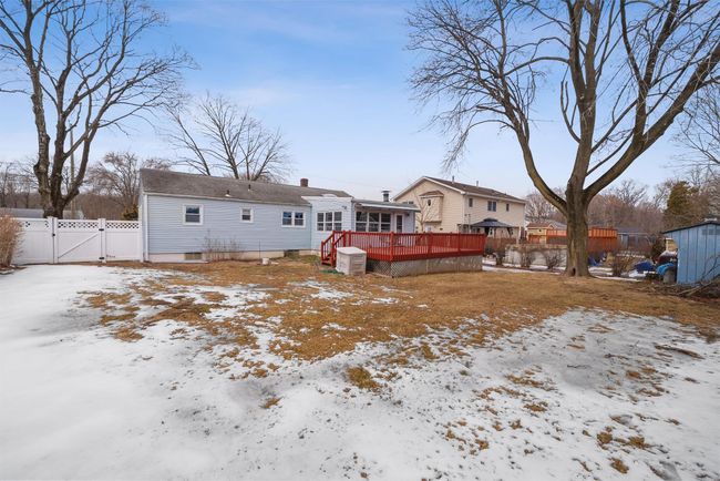 Snow covered property featuring central AC, fence, a wooden deck, a gate, and a chimney | Image 42