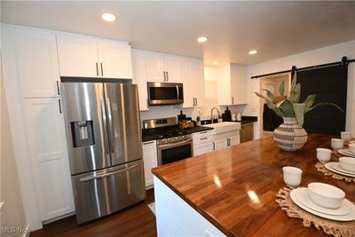 Kitchen with stainless steel appliances, sink, a barn door and white cabinets | Image 3