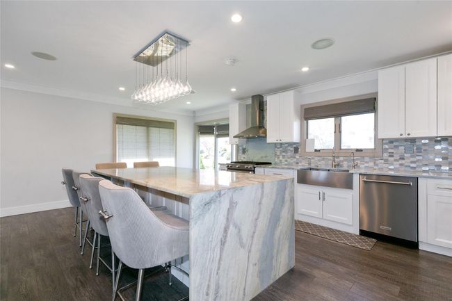 Kitchen featuring appliances with stainless steel finishes, wall chimney range hood, backsplash, and a sink | Image 8