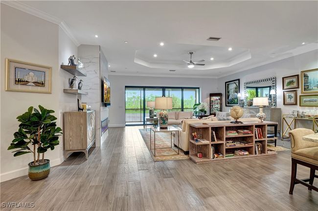 Featuring crown molding, light wide plank flooring, tray ceiling, and ceiling fan | Image 9
