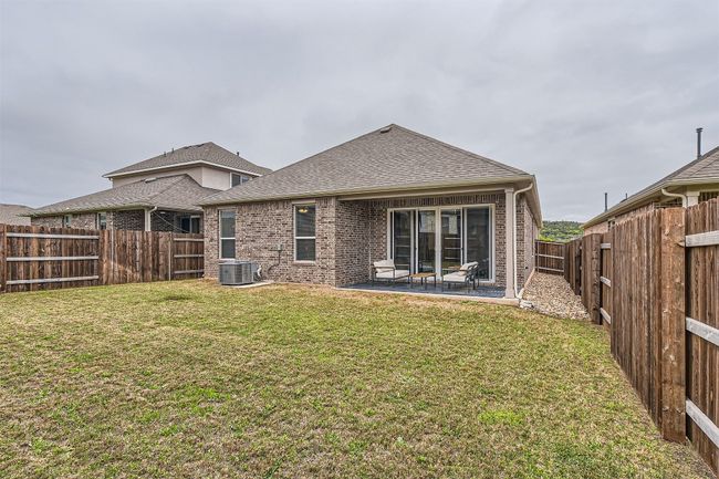 Back of house with brick siding, central AC unit, a fenced backyard, a yard, and roof with shingles | Image 23