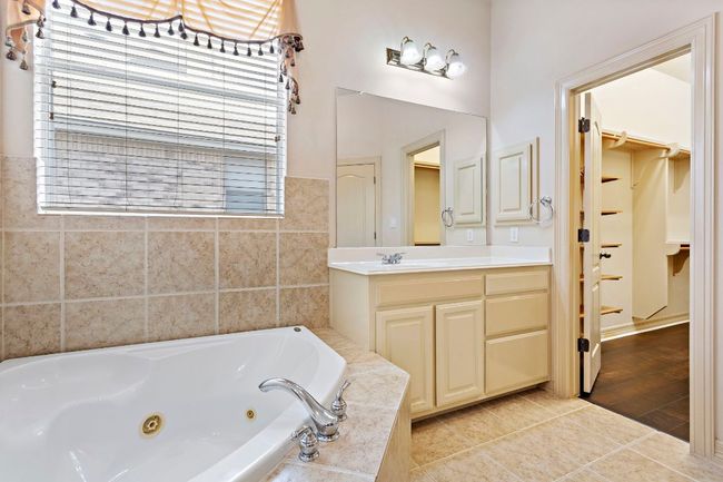 Full bath featuring a closet, vanity, tile patterned floors, and a jetted tub | Image 22