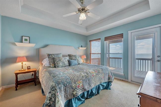 Wake up to panoramic water views in this tranquil primary bedroom, featuring a tray ceiling, soft coastal hues, and direct balcony access. A private retreat with front-row seats to every sunrise. | Image 22