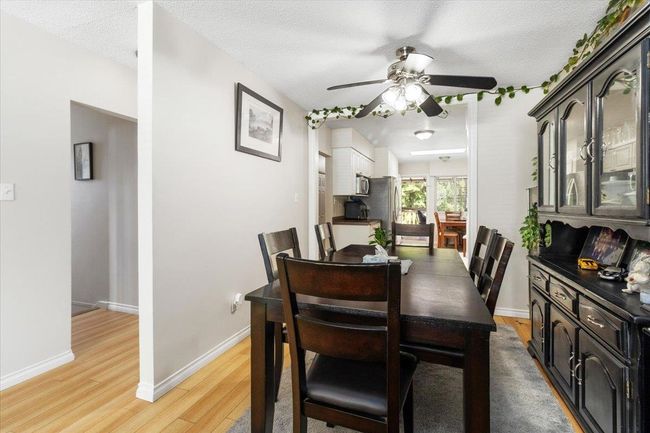 Dining area featuring a textured ceiling, light wood-style floors, baseboards, and ceiling fan | Image 9