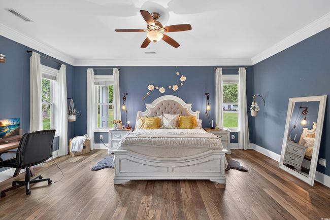 Bedroom featuring wood finished floors, crown molding, ceiling fan, and an office area | Image 19