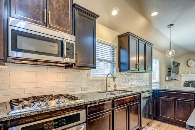 Kitchen with plenty of natural light, dark stone counters, lofted ceiling, stainless steel appliances, and a sink | Image 16