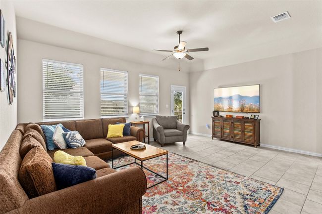 Living room with ceiling fan, light tile patterned floors, and healthy amount of natural light | Image 12