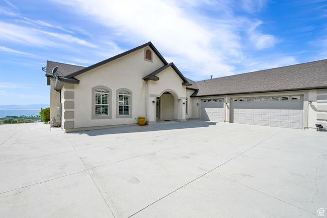 View of front of home with concrete driveway, stucco siding, roof with shingles, and a garage | Image 47