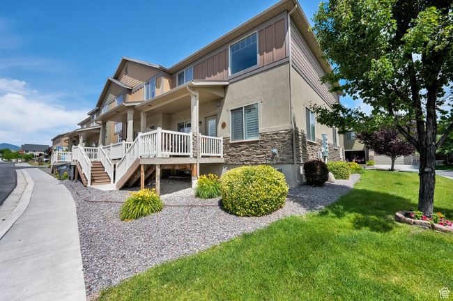 View of home's exterior with stone siding, a porch, stucco siding, a lawn, and stairway | Image 29