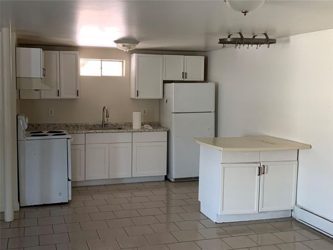 Kitchen featuring white appliances, white cabinets, under cabinet range hood, and a peninsula | Image 5