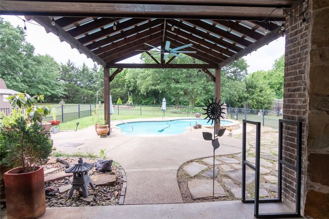 View of pool with a gazebo, a fenced backyard, a patio, view of wooded area, and ceiling fan | Image 34