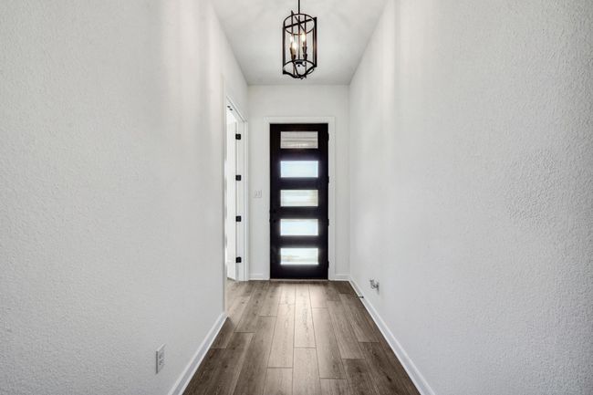 Entryway with dark wood-style flooring, a chandelier, and a textured wall | Image 19