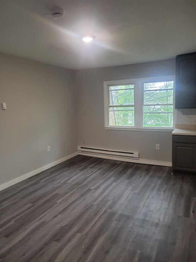 Spare room with a baseboard radiator, dark wood-style flooring, and baseboards | Image 17