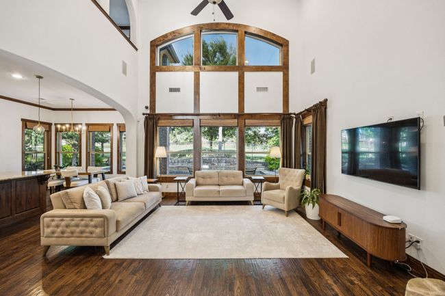 Living room featuring a high ceiling, dark wood-style flooring, a ceiling fan, a chandelier, and arched walkways | Image 14