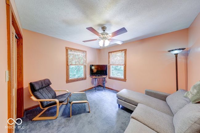 carpeted living area featuring ceiling fan and a textured ceiling | Image 35