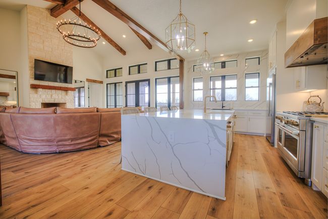 Kitchen featuring extractor fan, an inviting chandelier, white cabinets, high vaulted ceiling, and high end appliances | Image 13