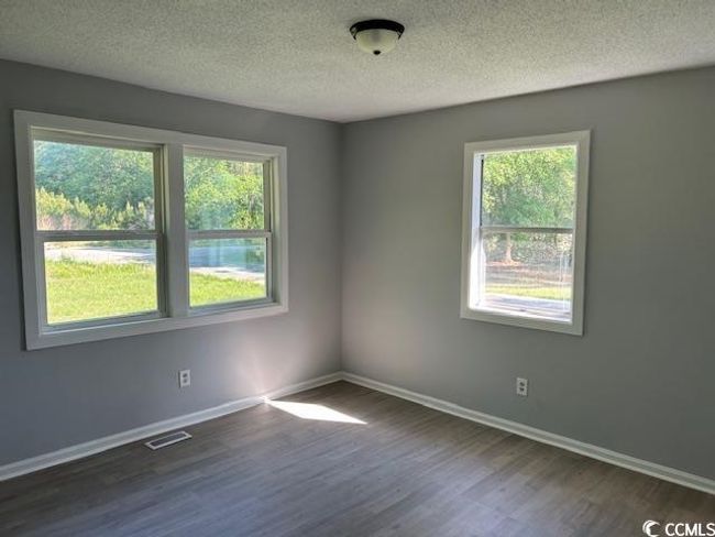 Unfurnished room featuring plenty of natural light, dark wood-style floors, baseboards, and a textured ceiling | Image 20