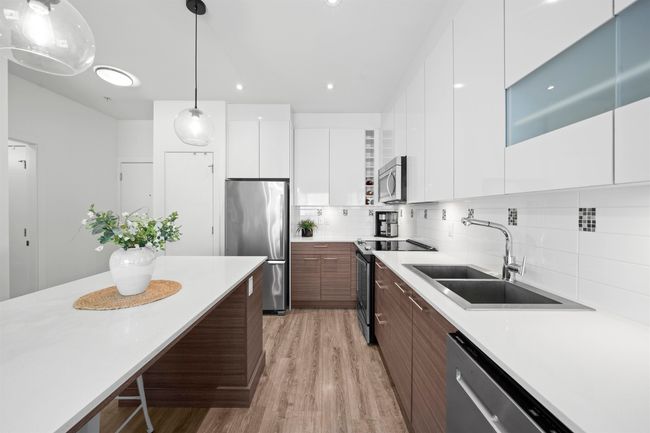 Kitchen featuring a sink, white cabinets, modern cabinets, light countertops, and appliances with stainless steel finishes | Image 9