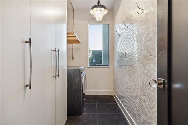 Even the laundry room has its own thoughtful design touches—featuring a full wall of gorgeous tile accented by strategically placed hooks for added function and style. As with the rest of the home, storage is abundant here too, making laundry day just a bit more enjoyable. | Image 15