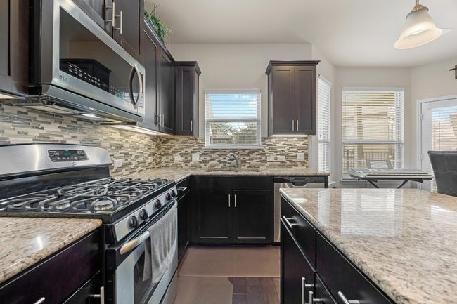 Also featuring sleek stainless steel appliances, decorative backsplash, under-lit upper cabinets, and a window over the kitchen sink with backyard views. | Image 15