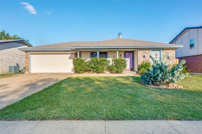 Single story home featuring a front yard, cooling unit, and a garage | Image 1