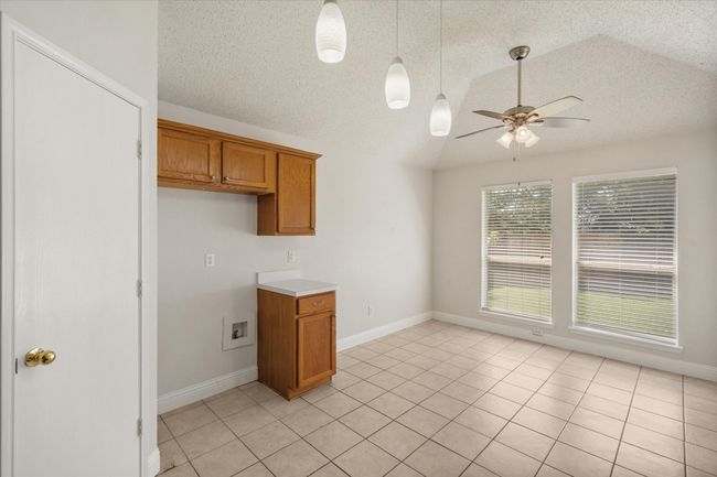 Bright and light eating area in Kitchen with lofted ceiling, a ceiling fan, and ceramic tile. | Image 9