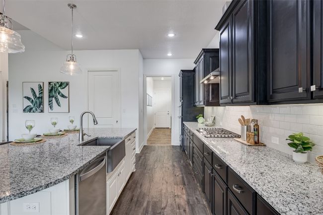 Kitchen featuring appliances with stainless steel finishes, dark wood-style floors, light stone counters, backsplash, and dark cabinetry | Image 10
