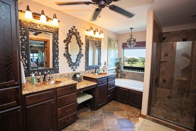 Ensuite bathroom featuring a shower stall, a garden tub, ceiling fan, and two vanities | Image 10