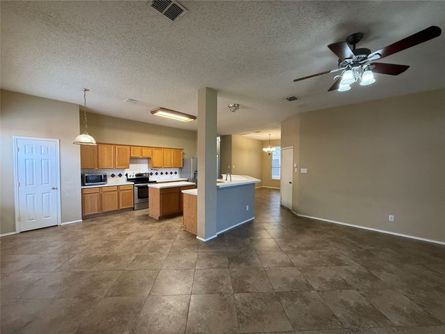 Kitchen with appliances with stainless steel finishes, baseboards, ceiling fan, light countertops, and decorative light fixtures | Image 8