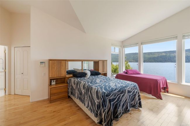 Bedroom with high vaulted ceiling, light wood finished floors, multiple windows, a water view, and baseboards | Image 27