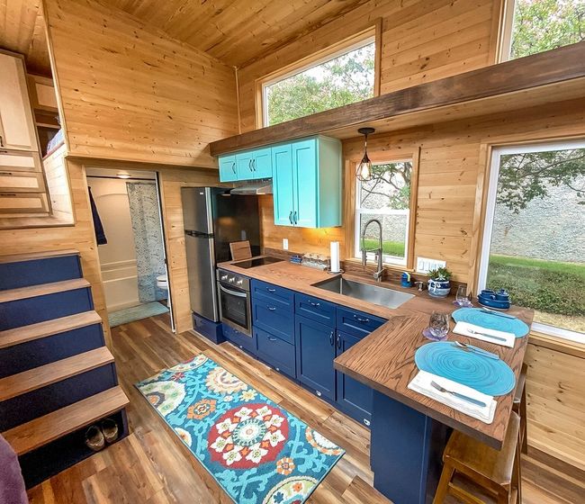 Kitchen featuring blue cabinets, appliances with stainless steel finishes, wooden ceiling, wood walls, and hanging light fixtures | Image 18