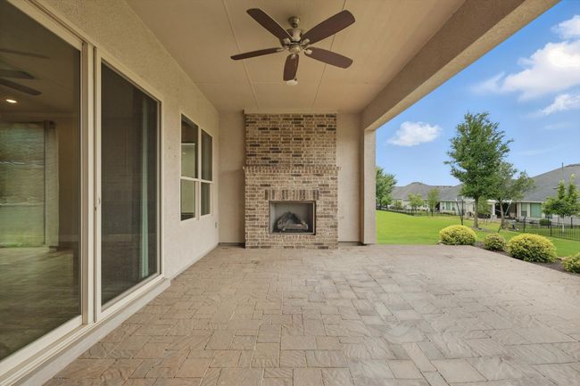 Covered back patio with fireplace, pavers and ceiling fan | Image 26