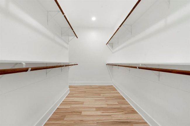 Spacious walk-in closet with wooden flooring, ample hanging space, and bright lighting. Ideal for organized storage. | Image 15