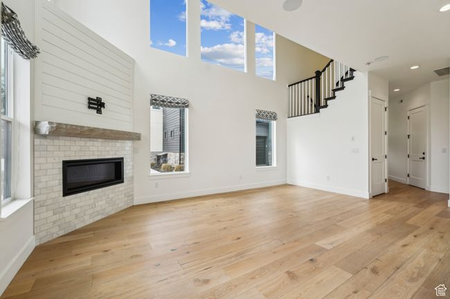 Unfurnished living room featuring a brick fireplace, light wood-style floors, and baseboards | Image 16