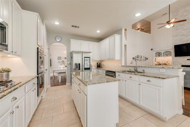 Kitchen with a sink, arched walkways, appliances with stainless steel finishes, a kitchen island, and ceiling fan | Image 14
