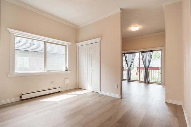Unfurnished bedroom with baseboard heating, wood finished floors, ornamental molding, and a closet | Image 14