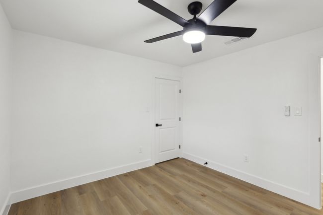Empty room with light wood-type flooring, baseboards, ceiling fan, and visible vents | Image 17