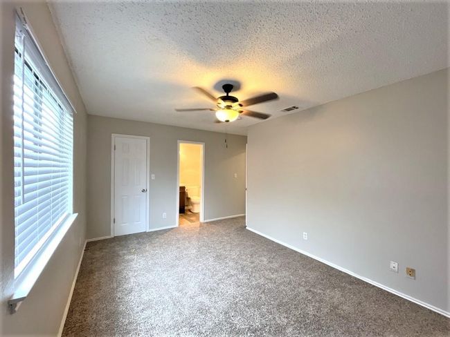 Unfurnished bedroom with carpet floors, baseboards, a textured ceiling, ensuite bath, and a ceiling fan | Image 11