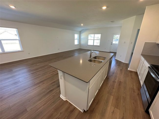 Kitchen featuring stove, a sink, white cabinets, open floor plan, and dark wood-type flooring | Image 6
