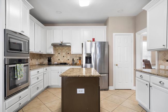 Kitchen featuring appliances with stainless steel finishes, light tile patterned flooring, backsplash, and white cabinets | Image 16